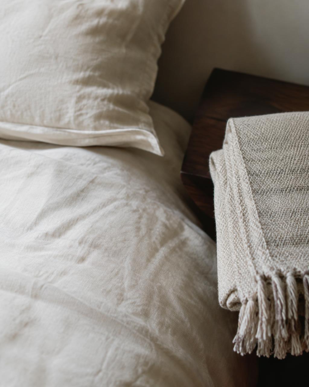 Linen bedding and a handwoven throw in soft window light